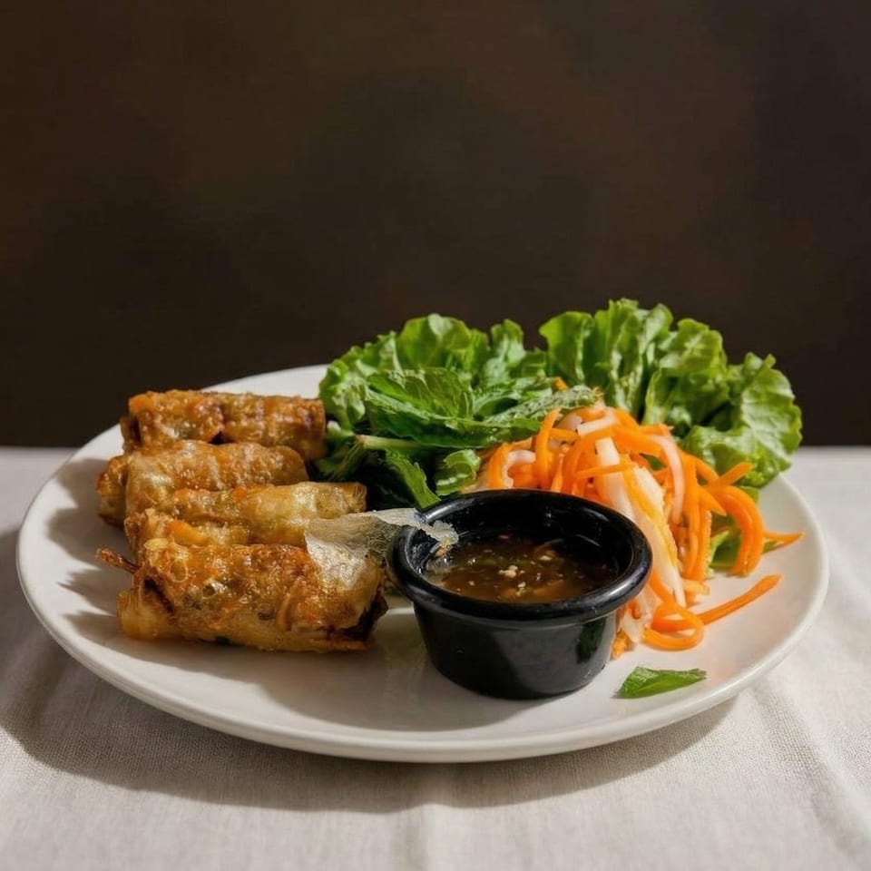 Crispy fried spring rolls, fresh lettuce, pickled carrots, and dipping sauce on a white plate.